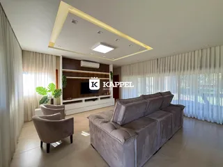 A sala de estar apresenta um sofá grande e cortinas brancas.