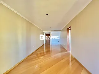 Foto de um corredor interno com piso de madeira clara e paredes claras.