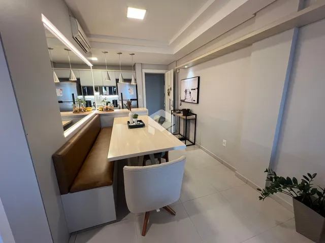 Interior de uma sala de jantar moderna com bancada e mesa de madeira clara.
