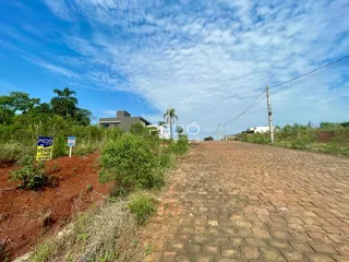 Vista externa de uma propriedade com caminho de tijolos e vegetação ao fundo.