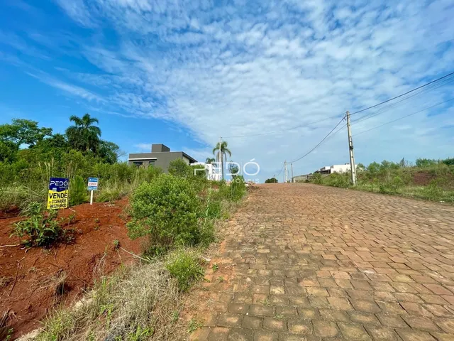 Vista externa de uma propriedade com caminho de tijolos e vegetação ao fundo.