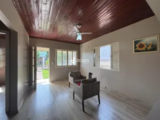 Uma sala de estar com piso de madeira clara e teto de madeira.