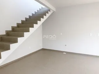 Ambiente interno de uma sala de estar com piso de cerâmica e escadaria.