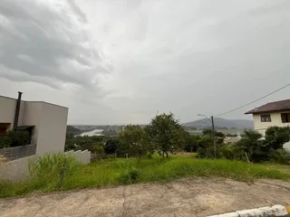 Vista externa de um terreno com grama e árvores sob um céu nublado.