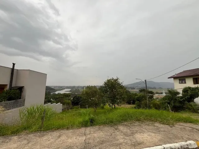 Vista externa de um terreno com grama e árvores sob um céu nublado.