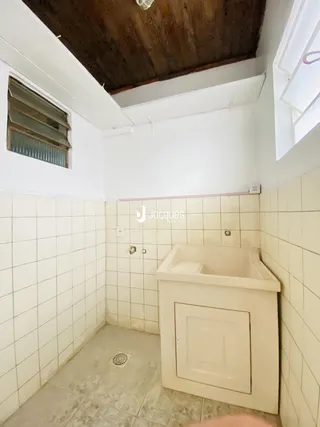 Foto de um banheiro com revestimento cerâmico e teto de madeira.