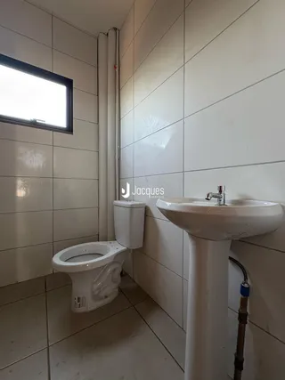 Interior de um banheiro com piso de cerâmica e azulejos brancos.