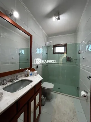 Foto do interior de um banheiro com box de vidro e bancada de mármore.