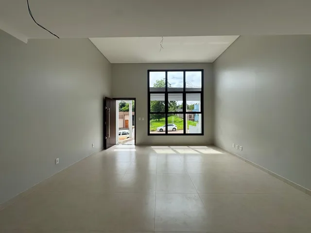 Sala ampla com piso claro e grande janela voltada para o exterior.