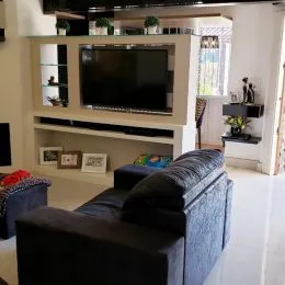 Sala de estar com sofá e televisão montada na parede.