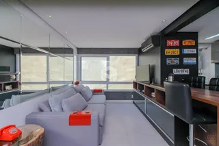 Sala de estar moderna com sofá cinza e grandes janelas.
