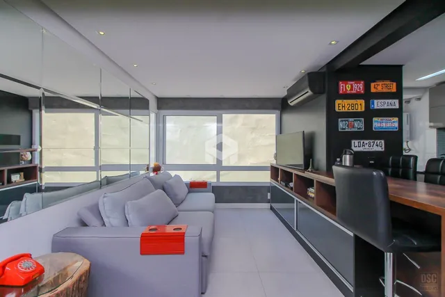 Sala de estar moderna com sofá cinza e grandes janelas.