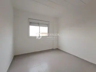 Vista interna de um cômodo vazio com paredes brancas e piso claro.