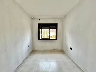 Um corredor interno com paredes brancas e piso de cerâmica.