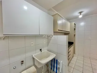 Banheiro com revestimento cerâmico branco e armários brancos.