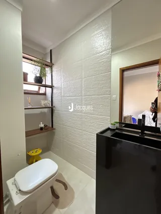 Banheiro com revestimento branco e piso claro.