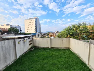 Vista de um quintal gramado cercado por muros de concreto em Lajeado.