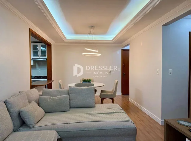 Sala de estar com sofá cinza e decoração clara em um imóvel no Brasil.