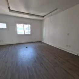 Sala de estar com piso de madeira e teto de gesso branco.