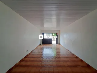 Corredor longo com piso de cerâmica e paredes brancas.