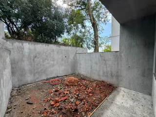 Área externa com solo irregular e materiais de construção espalhados.