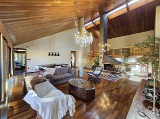 Sala de estar ampla com piso de madeira e teto alto.