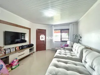 Sala de estar com sofá branco e televisão montada na parede.