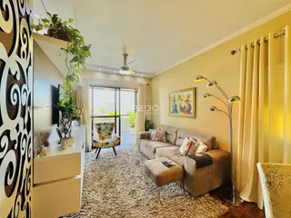 Uma sala de estar com piso de madeira e cortinas claras.