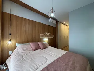 Quarto com cama grande e painéis de madeira na sala.