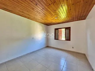 Ambiente interno de uma sala com piso de cerâmica e teto de madeira.