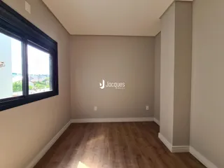 Vista interna de uma sala com piso de madeira e janela.