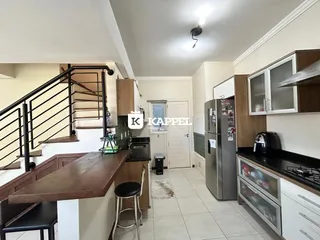 Foto da cozinha e área de jantar com escadaria em um apartamento.