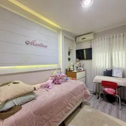 Quarto com cama rosa e cabeceira.