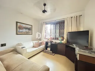 Sala de estar com sofá e televisão em um apartamento.