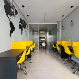 Hall de entrada com cadeiras amarelas e armários em vidro no fundo.