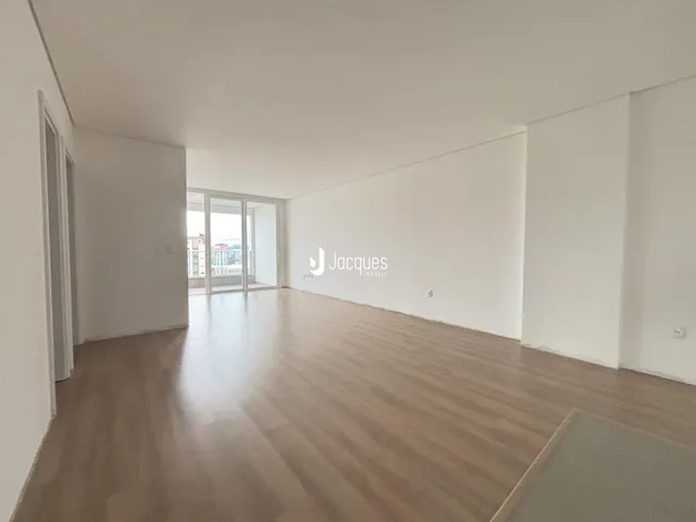 Ambiente interno de uma sala ampla com piso de madeira clara.