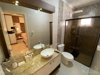 Banheiro com revestimento de azulejos e bancada de granito.