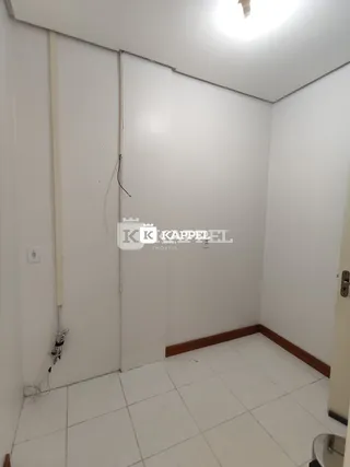 Foto de um corredor interno com piso de cerâmica branca.