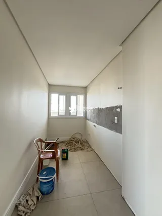Corredor interno com uma janela e objetos no chão.