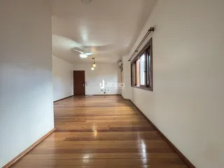 Corredor interno com piso de madeira e paredes brancas.