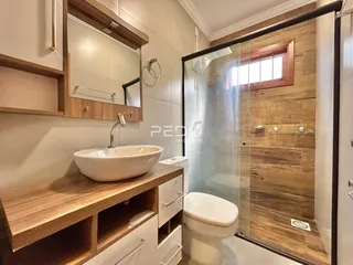 Foto de um banheiro com bancada de madeira e box de vidro.