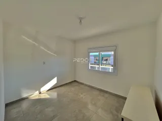 Ambiente interno de uma sala com piso de cerâmica e janela.