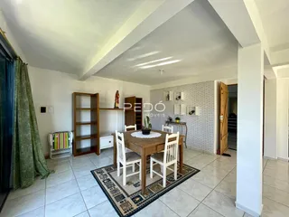 Sala de jantar com mesa de madeira e parede de tijolos na residência.