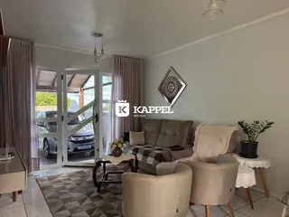 Sala de estar com sofá e cadeiras em um apartamento em Lajeado.