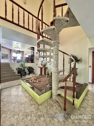 Foto de um corredor com escadaria e guarda-corpo em uma residência.