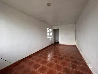 Hall de entrada com piso de ladrilho vermelho e paredes brancas.
