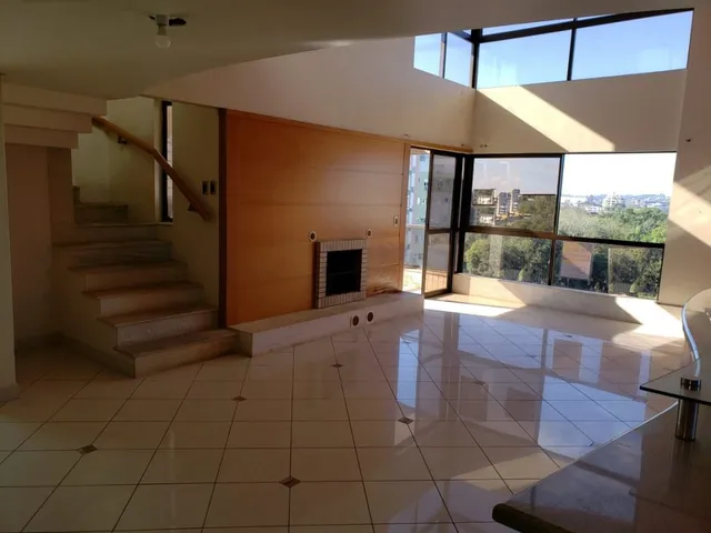 Uma sala ampla com piso de cerâmica e lareira em um imóvel em Lajeado.