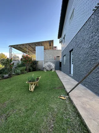 Fachada de uma casa com jardim gramado e estrutura de pérgola.