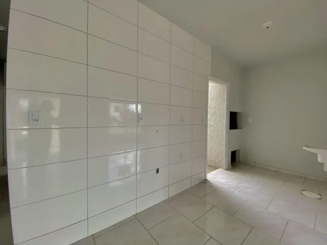 Ambiente interno com paredes brancas e piso claro em uma residência.