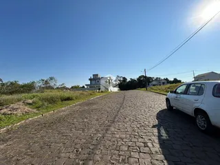 Uma rua pavimentada leva a uma casa branca no horizonte.
